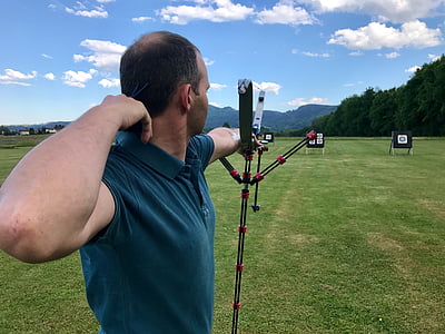 man holding bow in front of target at field thumbnail