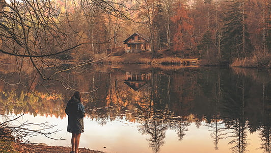 woman wearing jacket standing near body of water photography thumbnail
