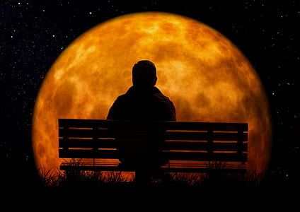 man sitting on bench facing moon thumbnail