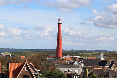 red lighthouse under white clouds and blue sky at daytime thumbnail