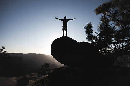 silhouette of man standing on huge rock thumbnail