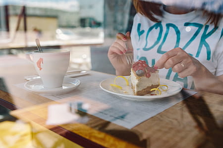 Woman Enjoying Cheese Cake and a Coffee with Fruits in a Cafeteria thumbnail