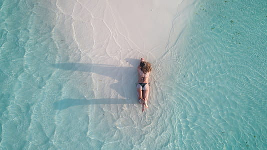 woman lying on sandbar taken at daytime thumbnail