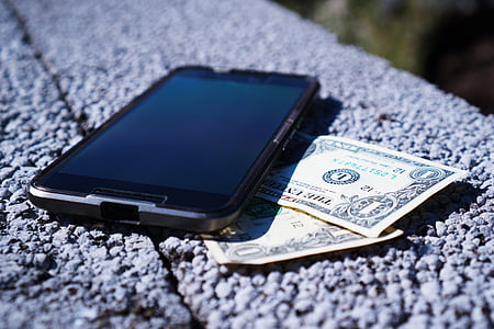 selective focus photographyt black Android smartphone and two 1 U.S. dollar banknotes thumbnail