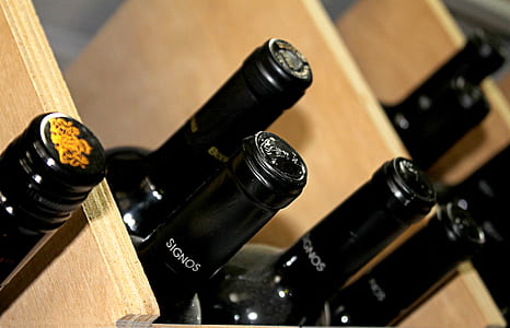 focus photo of black Signos bottles on brown wooden shelf thumbnail