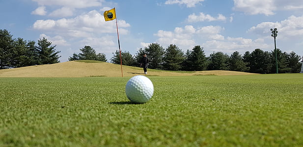 close-up photography of golf ball on green field at daytime thumbnail