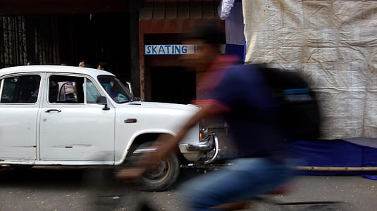 person riding bicycle near white sedan thumbnail