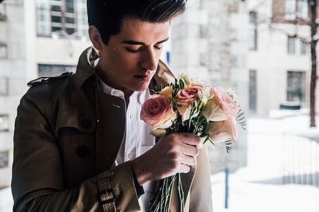 man wearing brown jacket and white dress shirt holding white and pink rose thumbnail