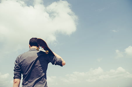 photograph of man in dress shirt carrying skateboard thumbnail