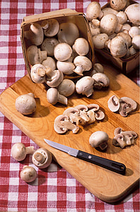 sliced mushrooms on brown wooden chopping board beside black and gray knife thumbnail