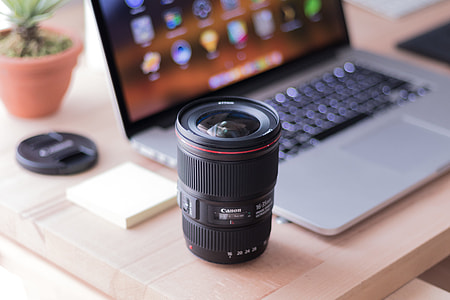 black Canon camera zooming lens beside MacBook Pro thumbnail