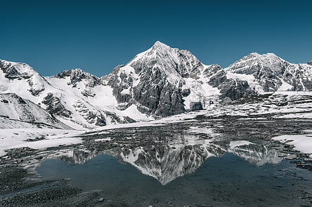 lake overlooking snow capped mountain at daytime thumbnail
