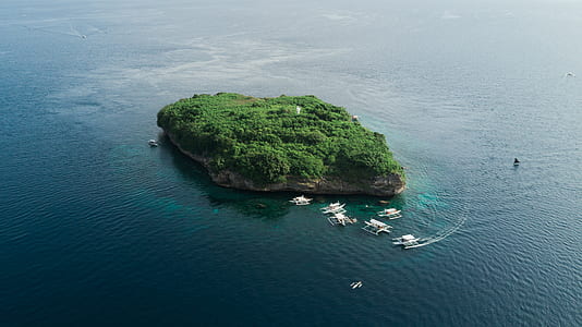 aerial photography of island beside boats with calm sea at daytime thumbnail
