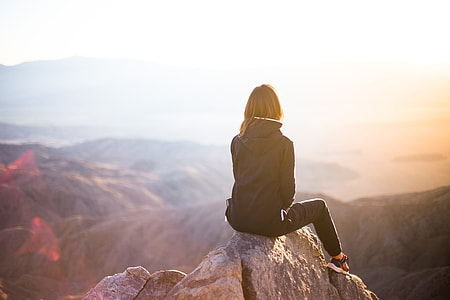 selective focus photography of woman in track suit sitting on cliff thumbnail