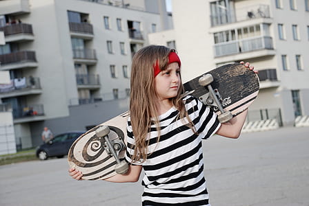 girl carrying skateboard during daytime thumbnail