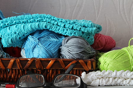 blue, green, and gray yarns on basket near black framed eyeglasses thumbnail