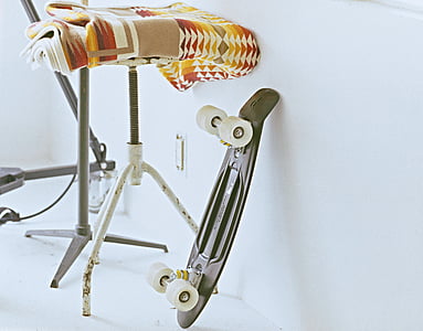 black cruiser board leaning on white wall near stool thumbnail