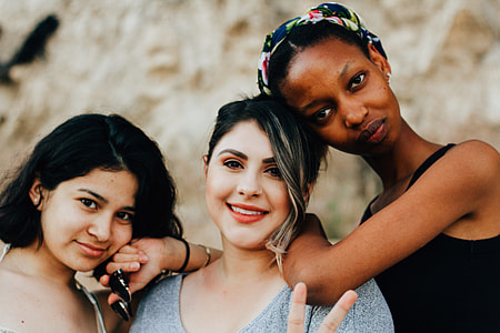 three women posing for photo in front of beige rock thumbnail