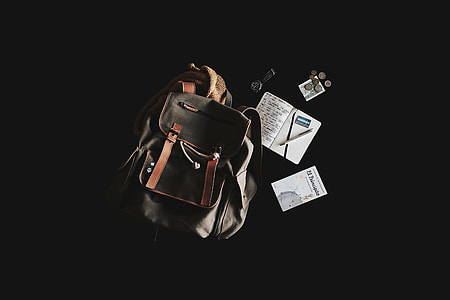 black and brown leather backpack beside books thumbnail