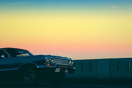 classic black vehicle parked near gray concrete wall thumbnail