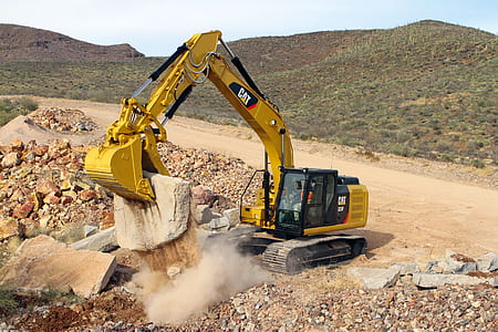 yellow and black Caterpillar excavator clipping stone on rocky hill during daytime thumbnail