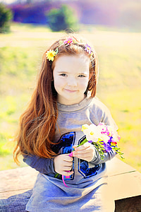 girl sitting on brown surface while holding flowers selective focus photo thumbnail