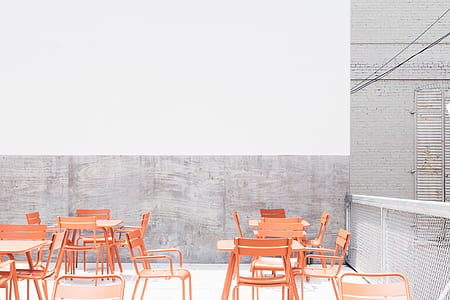 orange metal chairs and tables on rooftop during daytime thumbnail