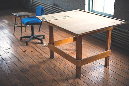 brown wooden drafting table beside rolling chair thumbnail