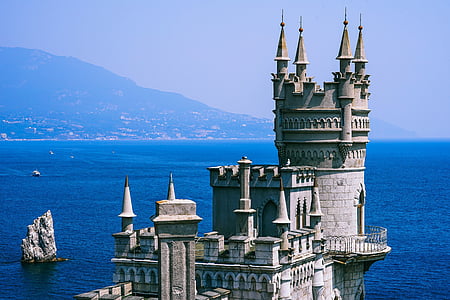 architectural photo of stone castle near body of water thumbnail