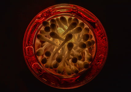 cotton swabs in red glass jar low-light photography thumbnail