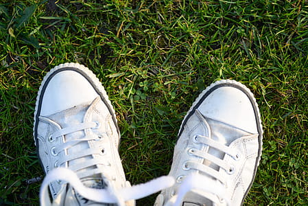 Pair of White Lace-up Sneakers on Top Green Grass thumbnail