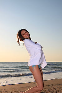 woman wearing teal bikini bottoms and white cardigan on beach thumbnail