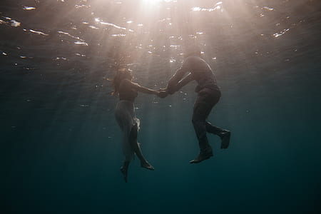 two people holding hands with bodies submerged in water while afloat thumbnail