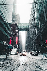 man crossing at road with a car passing by during snowy weather thumbnail