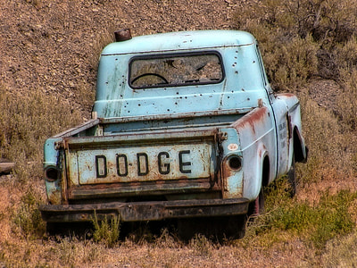 teal Dodge vehicle on green grass near mountain thumbnail