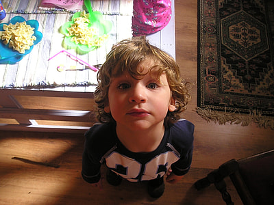 boy in white and black long-sleeved shirt standing behind table looking up thumbnail