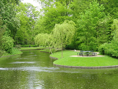 black metal table and bench near body of water and trees during daytime thumbnail