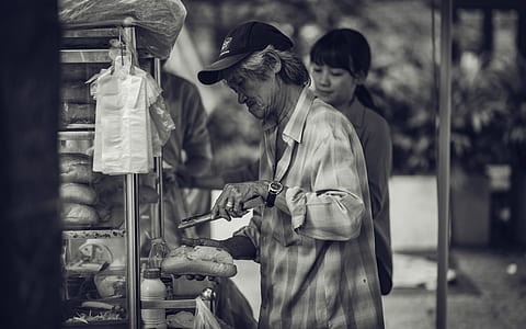 Man in Cap Holding a Pastry and Tong thumbnail