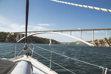 white sailboat on body of water under white bridge thumbnail