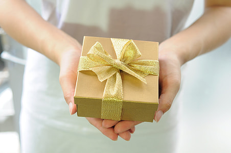 person holding gold box with ribbon thumbnail