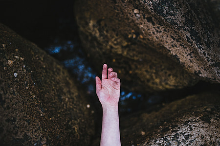 left hand of person with three brown rocks background thumbnail