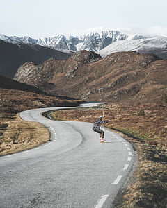 man skate on gray road in-front mountain thumbnail