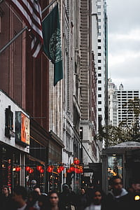 crowd walking beside brown concrete high-rise building thumbnail