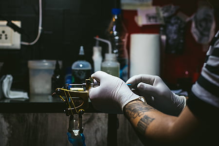 lowlight photography of person holding tattoo machine thumbnail