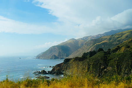 mountains beside sea under cloudy sky thumbnail
