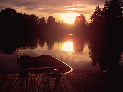 boat floating on water beside dock during golden hour thumbnail