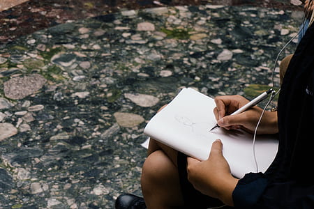 person holding white notebook and pen thumbnail