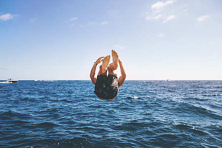 man jumping and diving on sea at daytime thumbnail