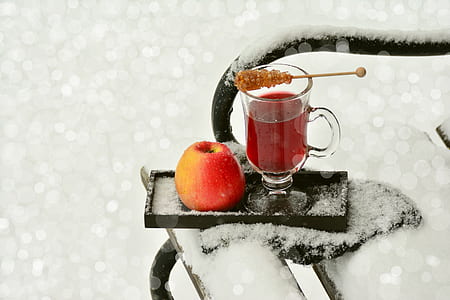 clear glass footed mug and red apple on black wooden ice covered tray thumbnail
