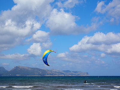blue and yellow parachute near body of water under blue sky thumbnail